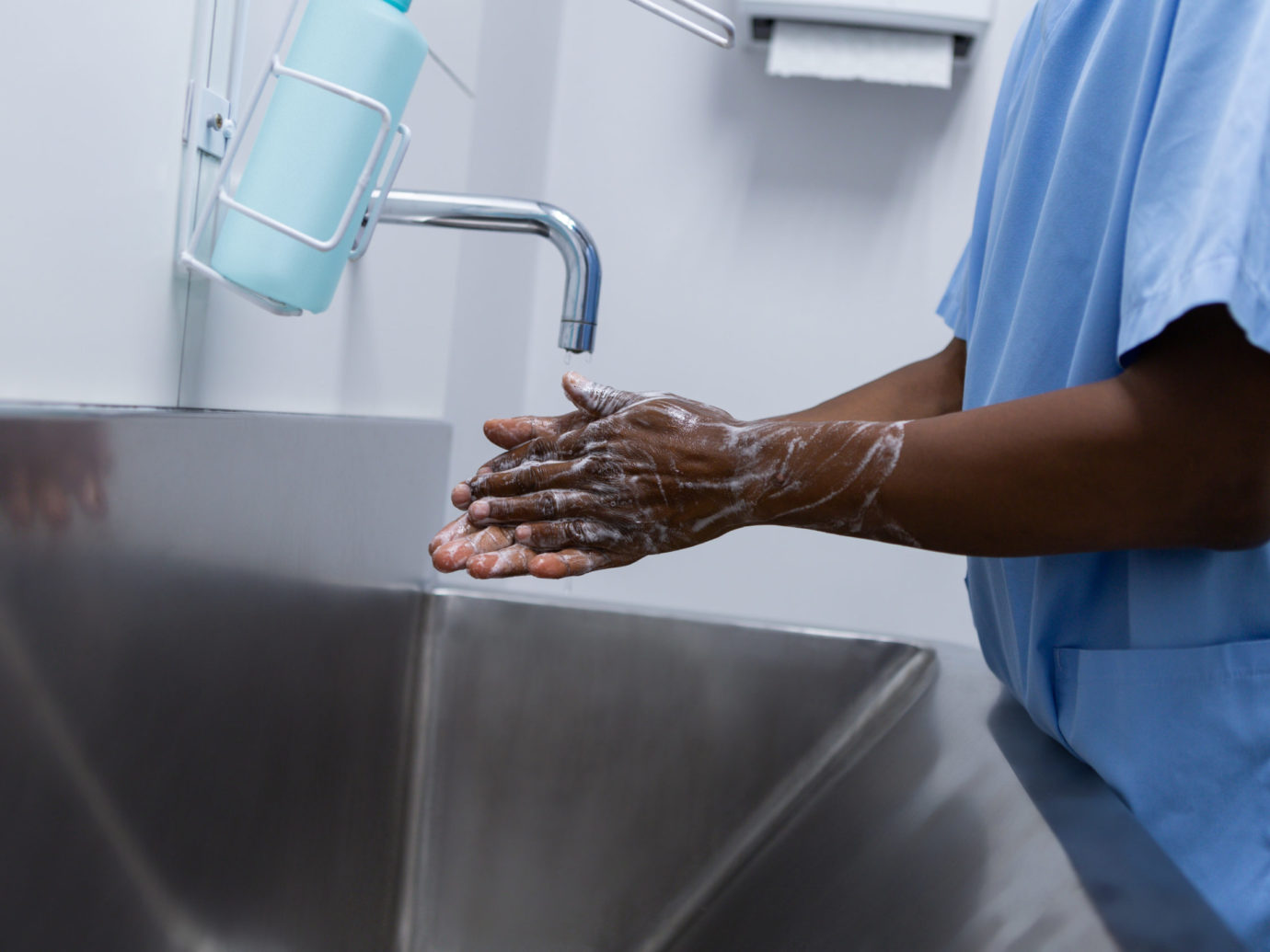 Male surgeon washing hands in sink at hospital