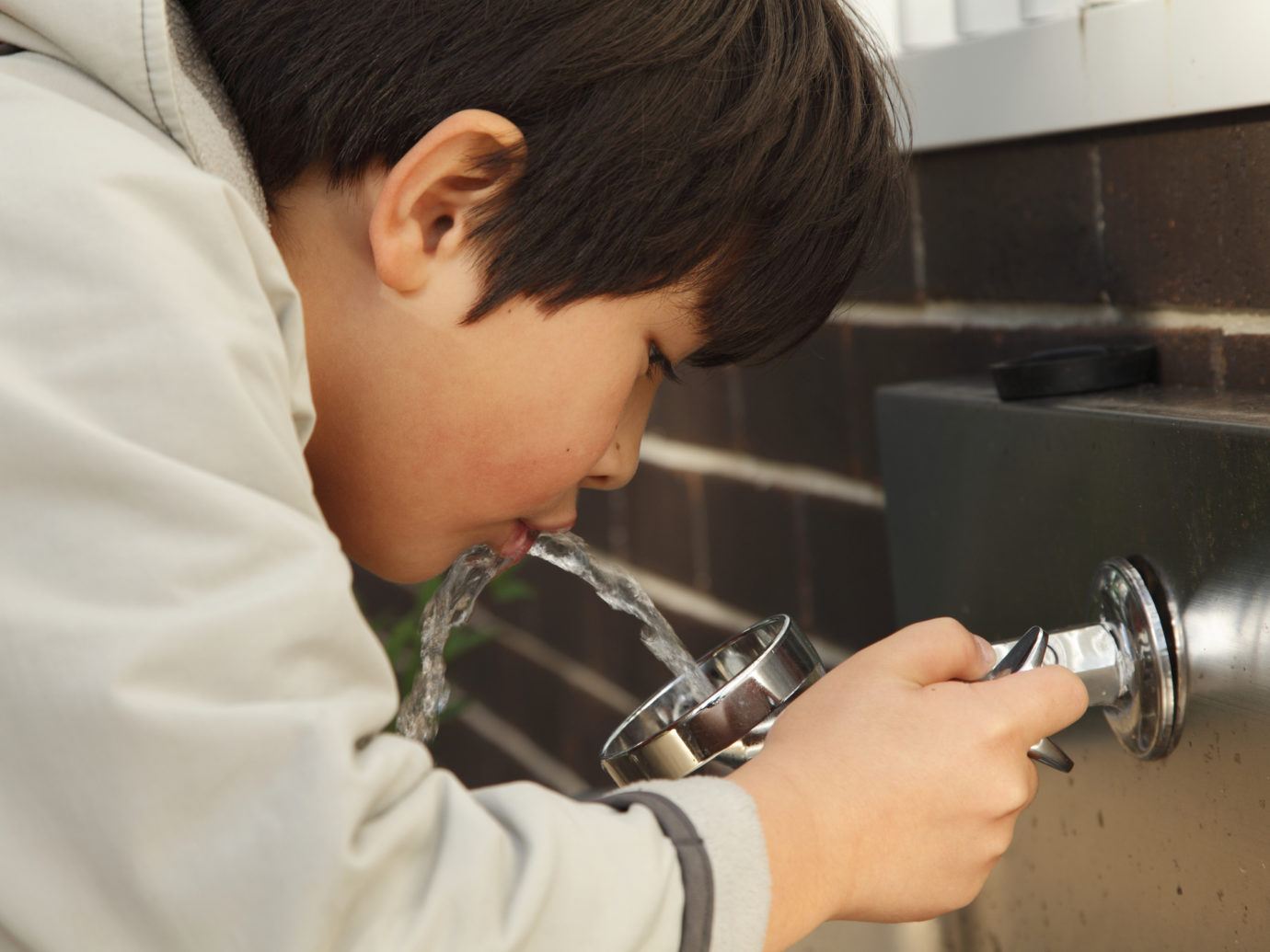 Boy drinking from a water fountain