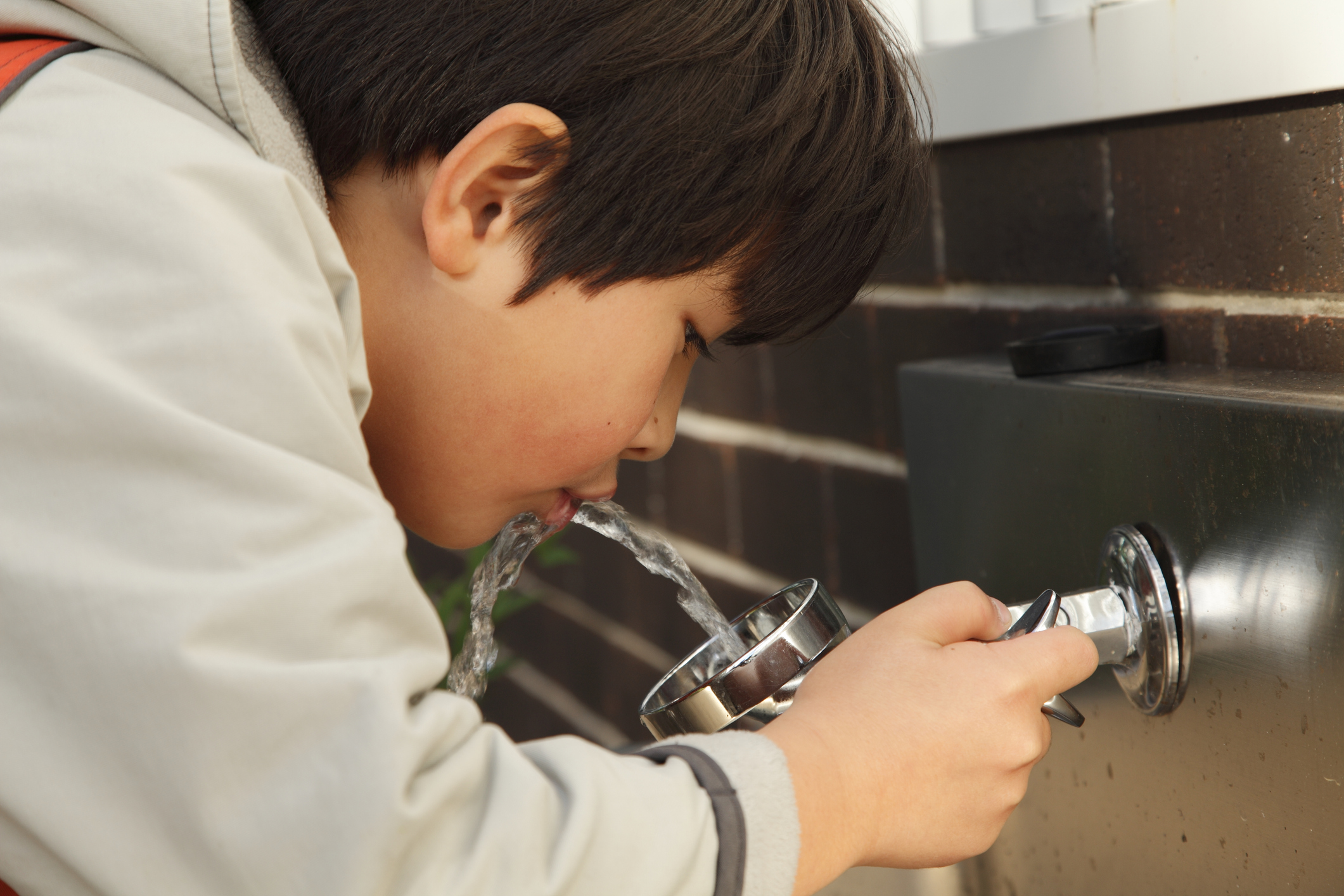 Boy drinking from a water fountain