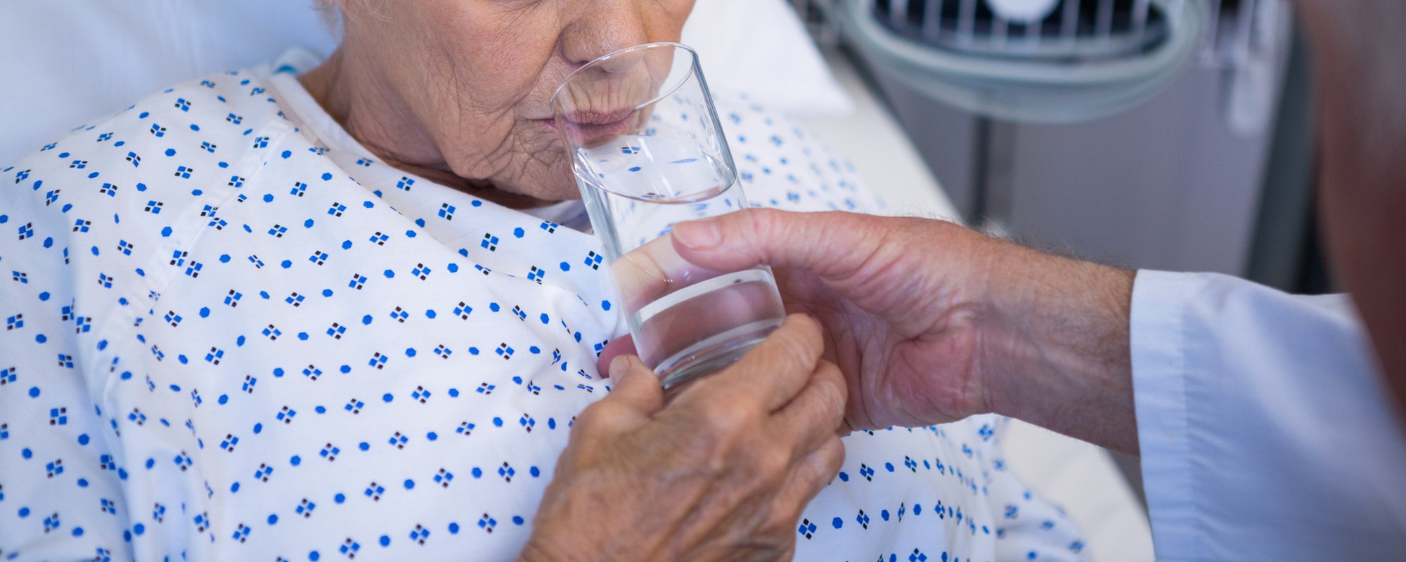 Doctor giving glass of water to senior patient
