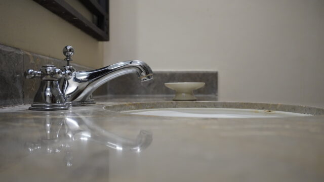 Interior water flowing from modern chrome stainless steel tap faucet in wash basin